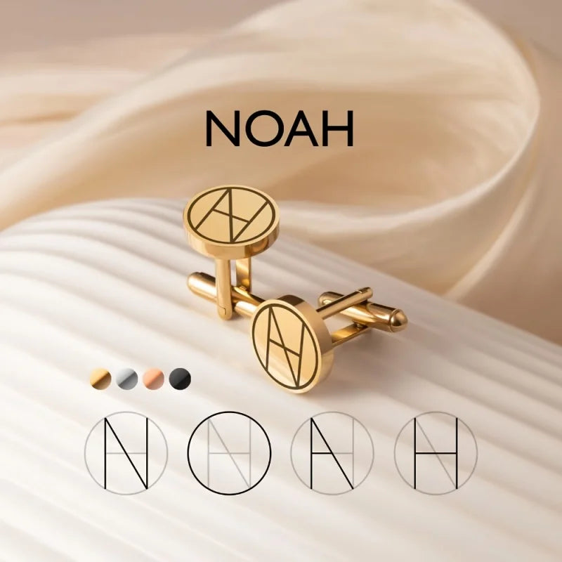 Gold cufflinks with a circular engraved 'NOAH' monogram, displayed on a cream-colored ribbed surface with draped beige fabric in the background. Four color options for the cufflinks are shown below.