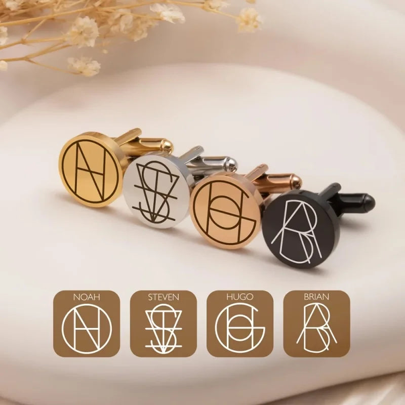 Four round cufflinks displayed on a soft cream surface, each with a different monogram design and metal finish: gold with white, silver with black, rose gold with white, and black with white. Below the cufflinks are four labeled name cards reading Noah, Steven, Hugo, and Brian.
